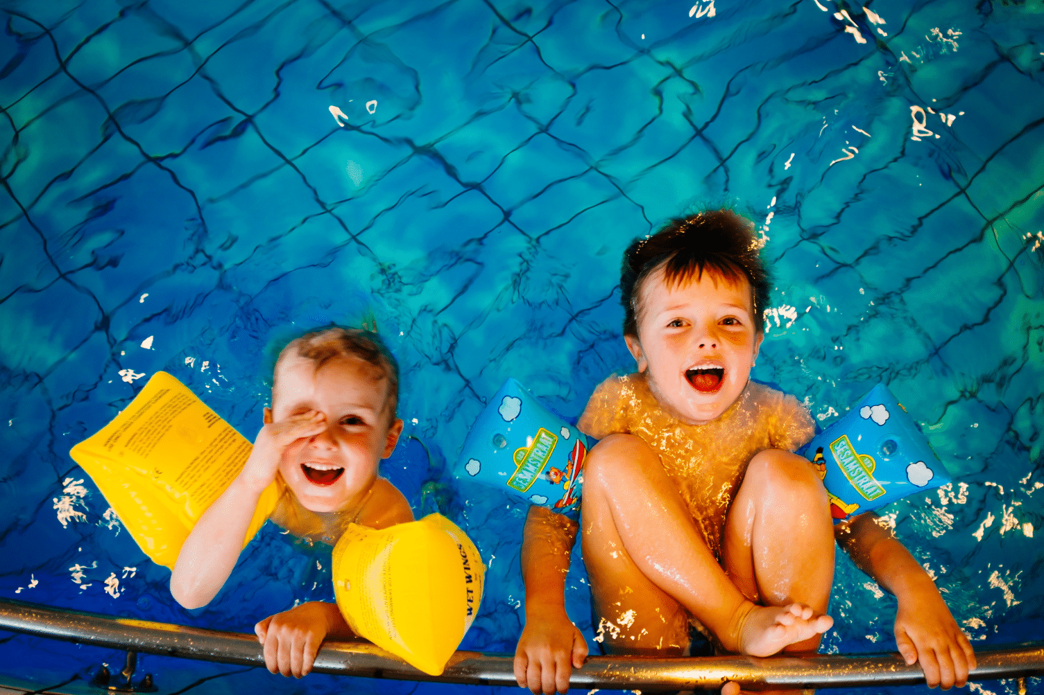 Twee kinderen met zwembandjes om hangen aan de railing